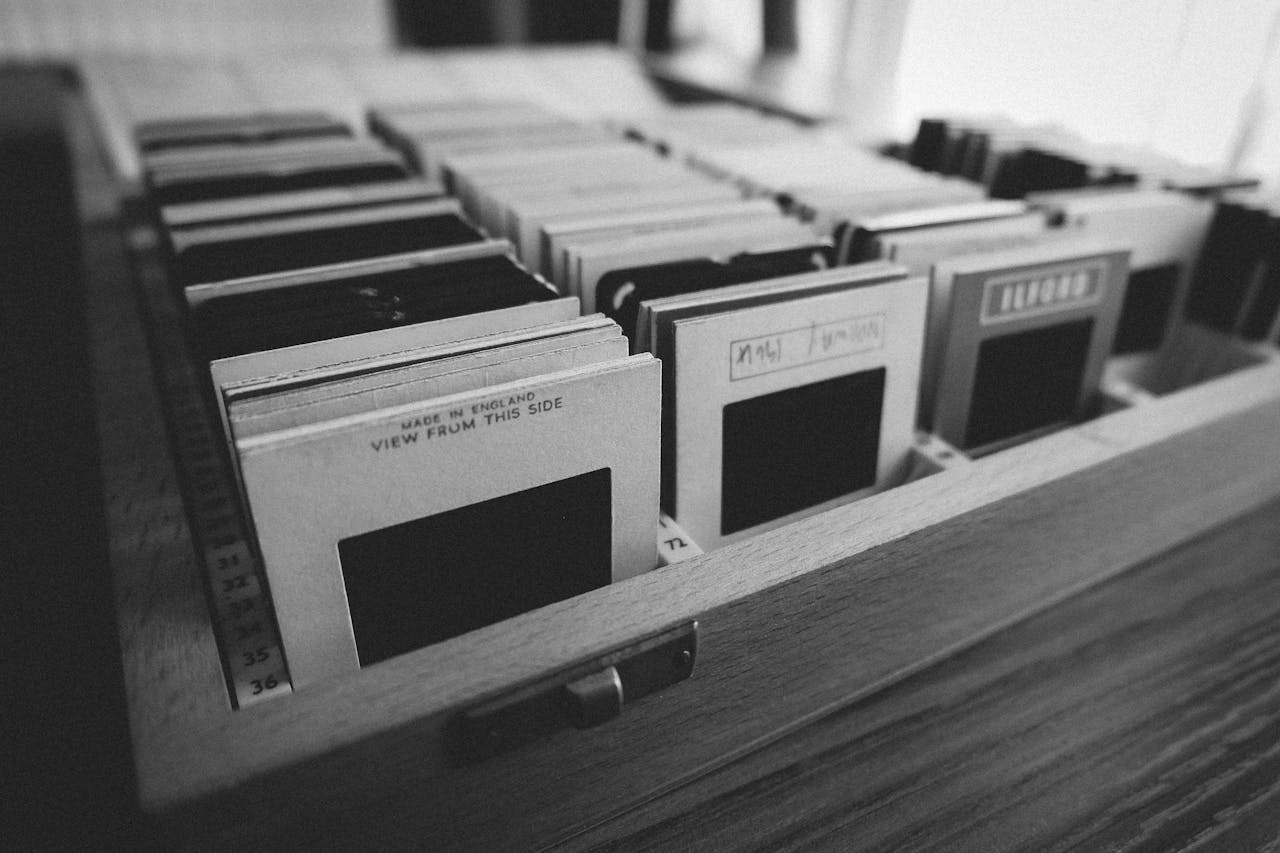 services-02 Black and white photo of vintage photography slides organized in a wooden box.