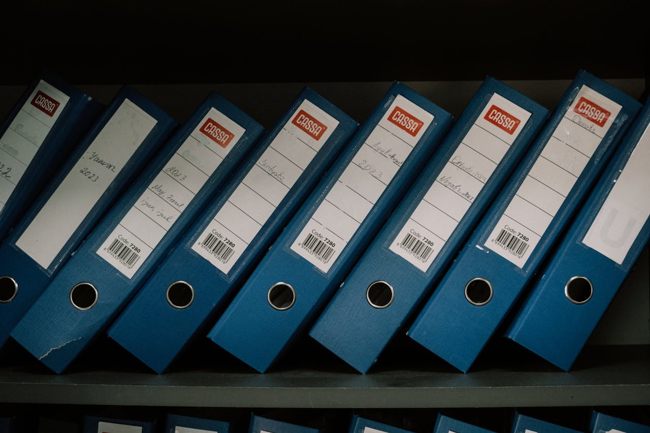 heros-img Neatly arranged blue office binders labeled with dates and names for organized storage.